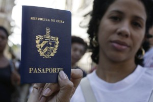 A woman shows her new passport while standing with others outside a passport office in Havana